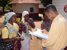 Man with a clipboard talking to woman in a village